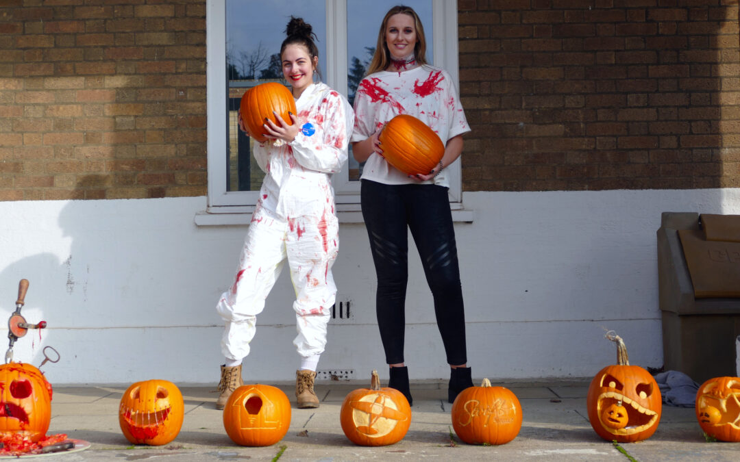 SEP staff Marie and Phoebe pose in Halloween costumes with pumpkin carving entries